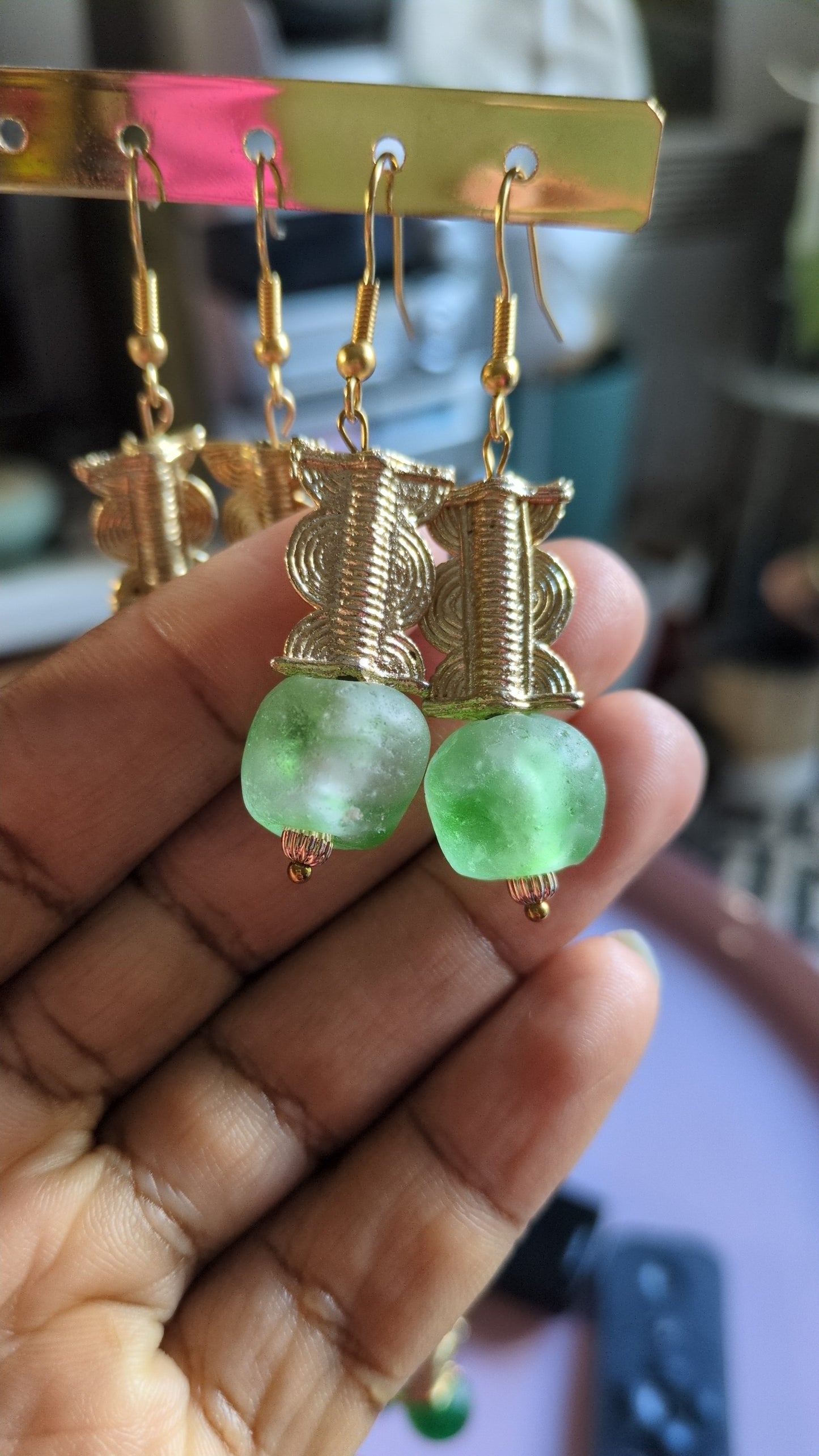 Ces boucles d'oreilles réalisées artisanalement sont composées d'une perle translucide vertes d'eau ainsi qu'une perle doré ( poids Akan ) en laiton.