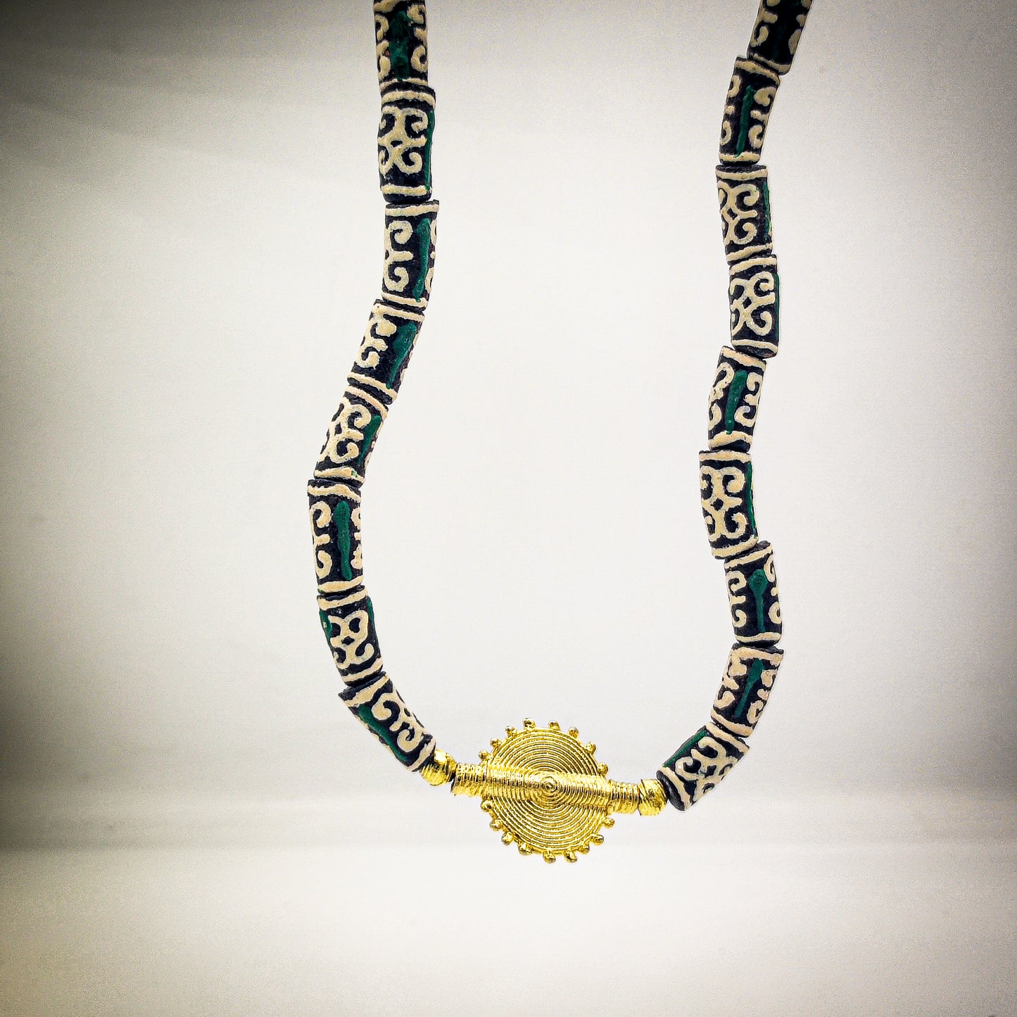 Les perles vertes du collier arborent un motif africain riche de significations : le "Dwennimen", qui signifie "cornes de bélier".
