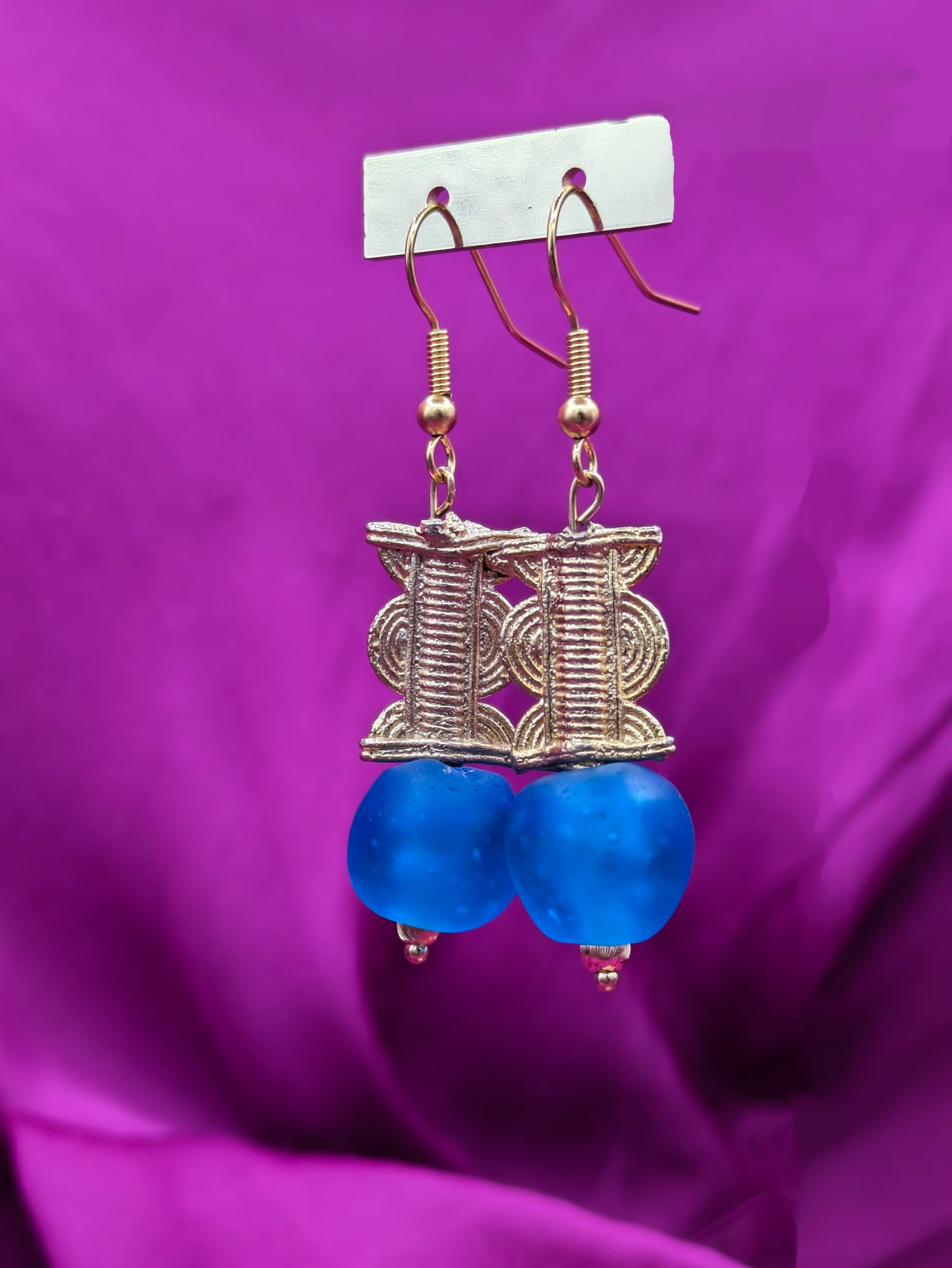 Boucles d'oreilles composées d'une perle translucide bleue pastel ainsi qu'une perle doré ( poids Akan ) en laiton.