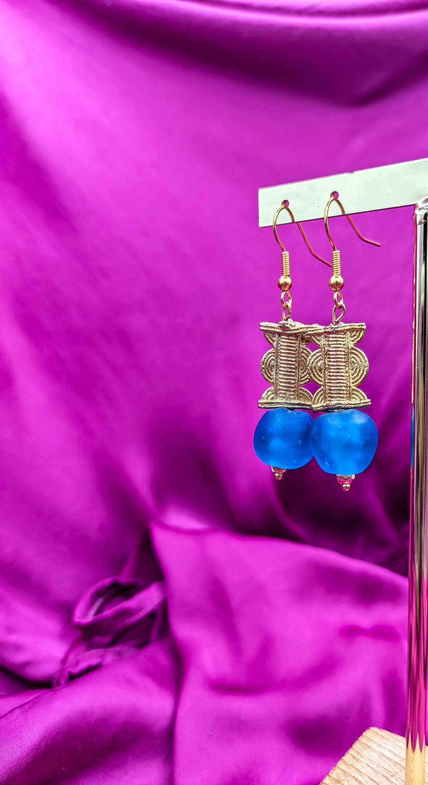 Boucles d'oreilles réalisées composées d'une perle translucide bleue pastel ainsi qu'une perle dorée ( poids Akan ) en laiton.