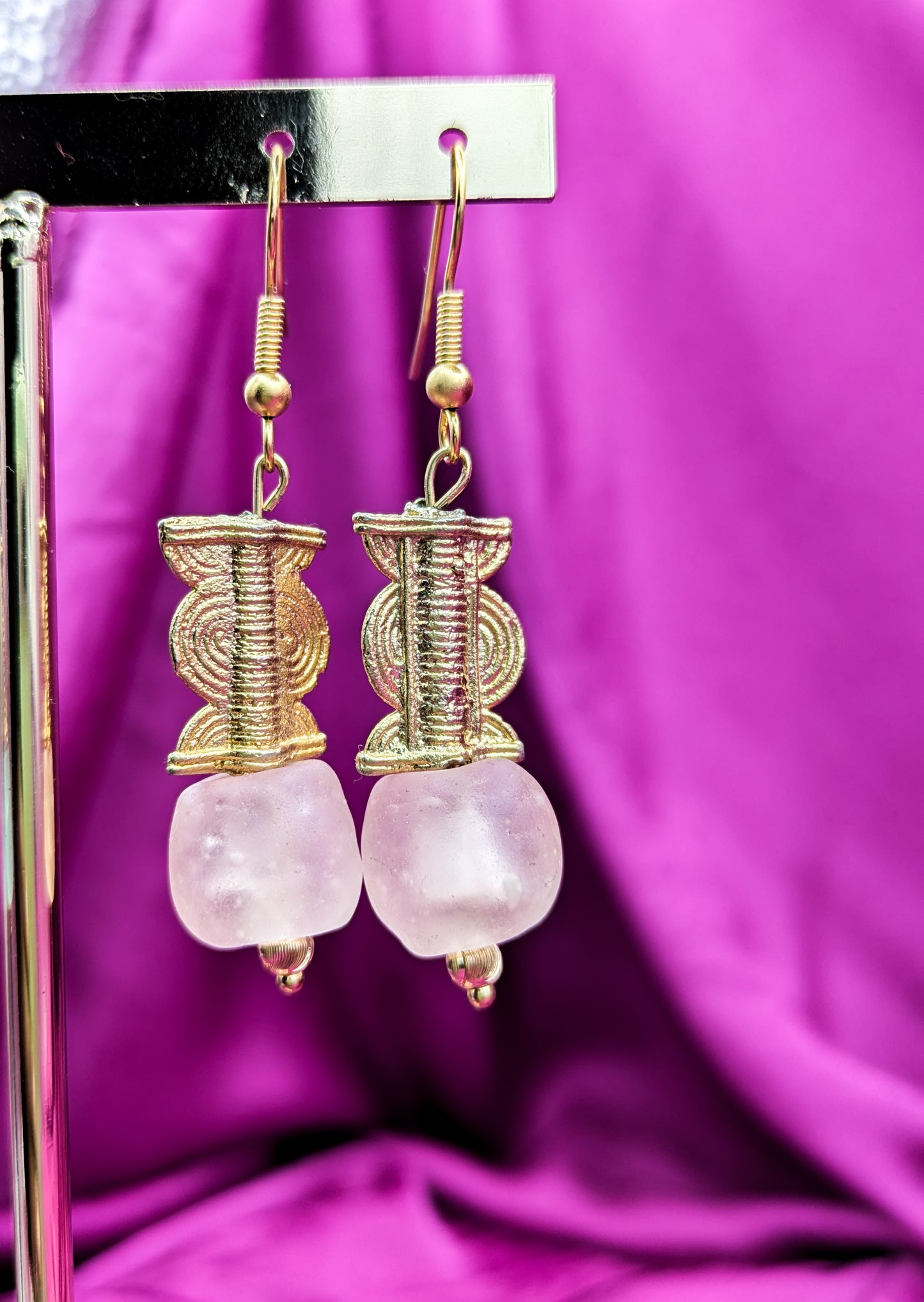 Boucles d'oreilles composées d'une perle translucide rose pastel ainsi qu'une perle dorée ( poids Akan ) en laiton.