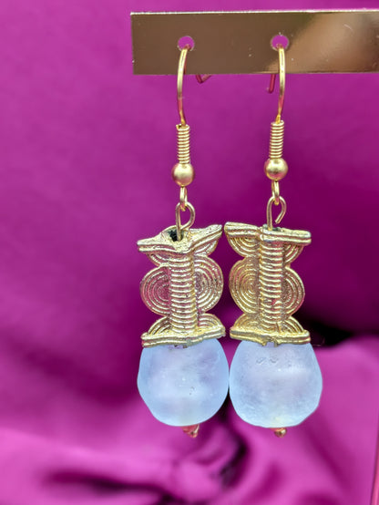 Ces boucles d'oreilles réalisées artisanalement sont composées d'une perle translucide bleue pastel ainsi qu'une perle doré ( poids Akan ) en laiton. 