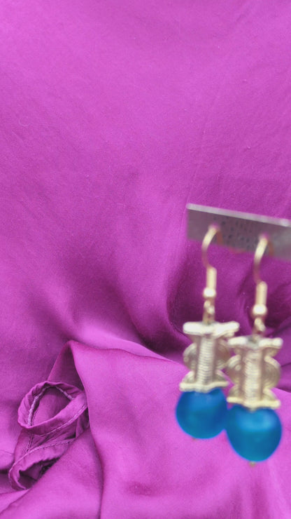 Boucles d'oreilles composées d'une perle translucide bleue pastel ainsi qu'une perle dorée ( poids Akan ) en laiton. 