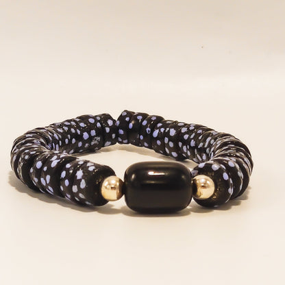 Ce bracelet bleu, réalisé artisanalement à partir de perles de verres recyclés est composé de perles bleues à pois, surmonté d'une perle noir et deux petites perles en argent.